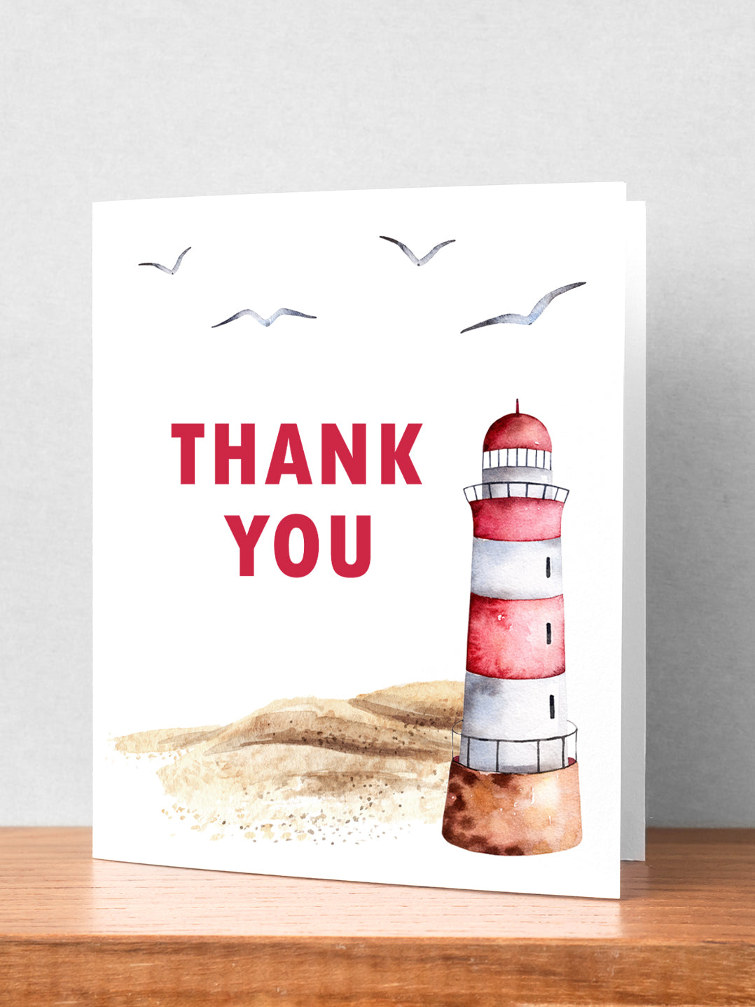 "A picturesque sandy beach with a red and white lighthouse set against a serene coastal backdrop, complemented by a heartfelt thank you in Red Lettering card design, evoking gratitude and a sense of calm seaside appreciation."