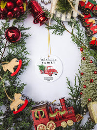 White circular ceramic ornament with the words Our First Christmas As Mr. & Mrs. followed by the family name in the center and the year. There is a red truck and Christmas Tree under name.  Black cursive font.  Ships with gold threaded ornament tie.
